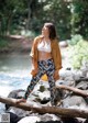 A woman standing on a log in the woods.