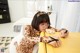 A woman in a leopard print pajamas sitting at a yellow table.