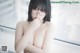 A naked asian woman wearing glasses posing in front of a window.