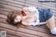 A woman in a school uniform laying on a wooden floor.