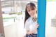 A woman in a school uniform leaning against a blue door.