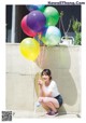 A woman kneeling down with a bunch of balloons.