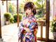 A woman in a kimono standing in front of a window.