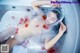 A woman laying in a bathtub covered in rose petals.