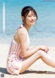 A woman sitting on the beach in a striped dress.