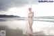 A woman in a wedding dress standing on the beach.