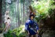 A woman in a blue kimono standing in the woods.