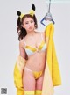 A woman in a yellow and white lingerie holding a yellow towel.