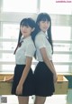 Two young women in school uniforms standing next to each other.