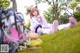 A woman laying on the grass with a backpack and a stuffed animal.